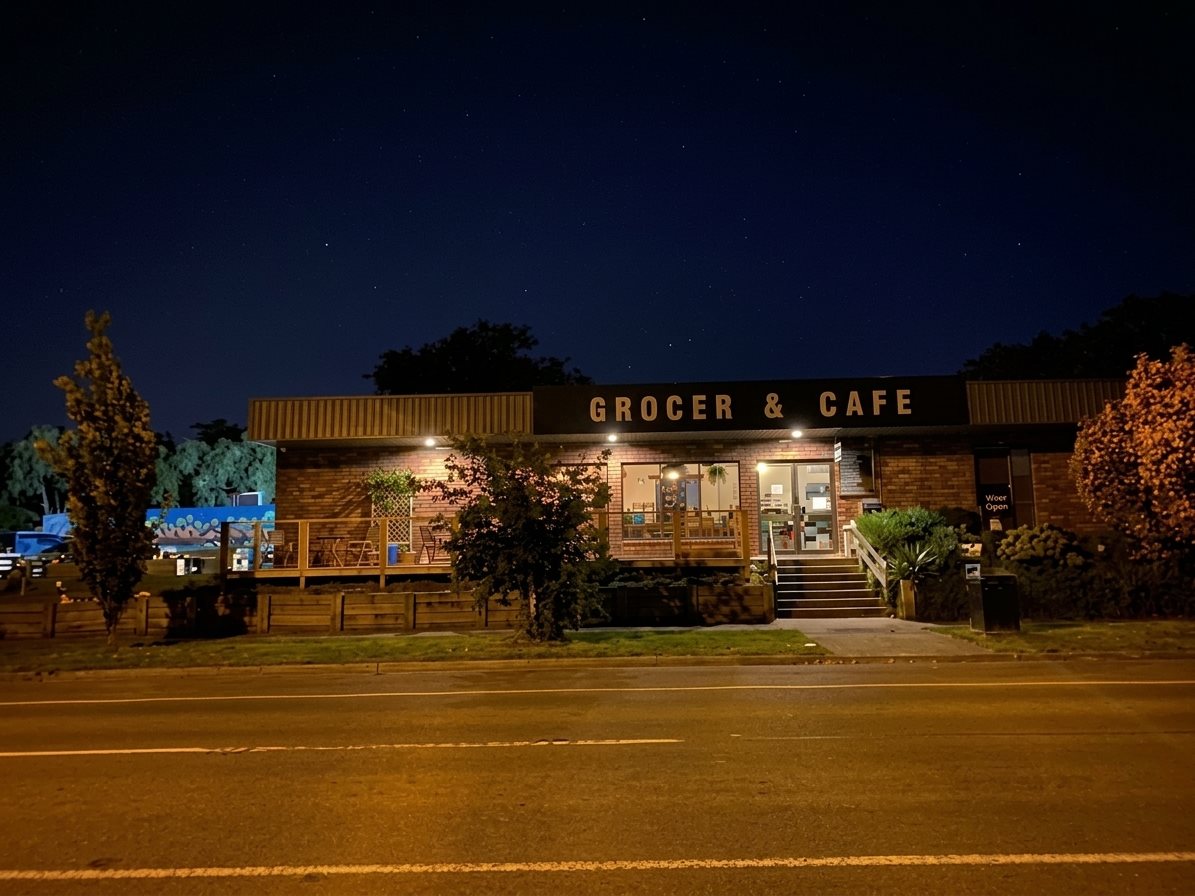 Grounded Grocer & Cafe at night, the Grocer & Cafe sign lit up under a starry sky